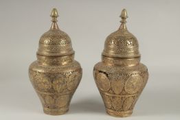 A PAIR OF PERSIAN QAJAR OPENWORKED LIDDED BRASS JARS, decorated with figures and floral motifs, 28cm