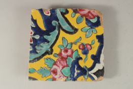 AN EARLY 19TH CENTURY PERSIAN YELLOW GLAZED POTTERY TILE, 18cm x 18cm.