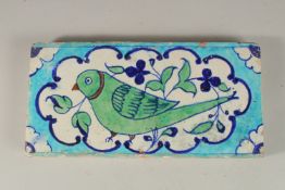 A RARE EARLY 19TH CENTURY NORTH INDIAN MULTAN POTTERY TILE, depicting a green parrot, 30cm x 15cm.