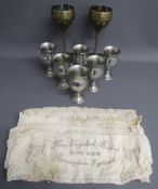 Pair of Brass goblets with peacock design, 6 Tudric pewter ware goblets and 5 cloths