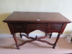 An Edwardian side table in mahogany having three drawers, turned legs united by x shaped stretcher,
