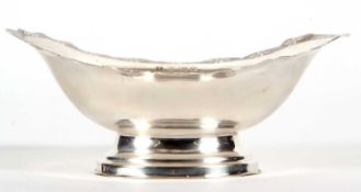 An Elizabeth II silver small pedestal dish of oval form having a shaped border, chased and