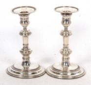 A pair of Elizabeth II silver candlesticks in Georgian style having knopped pillars and filled