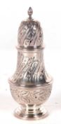 A hallmarked silver caster of baluster form, having a pull off pierced lid with urn finial, chased