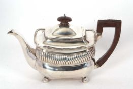 A George III silver teapot of oval form having gadrooned rims with part fluted decoration to the