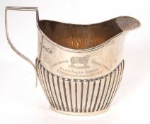 An early 20th Century silver cream jug of oval form with part fluted decorated body and reeded