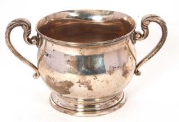 A George V twin handled silver sugar bowl of plain baluster form with two cast scroll handles on a