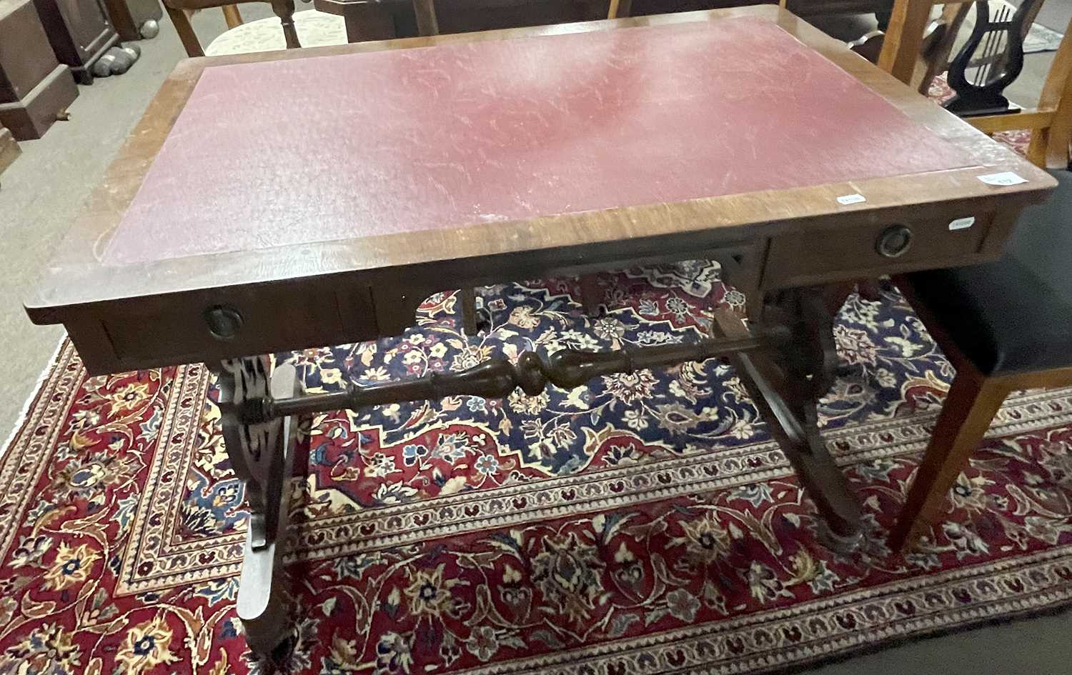 A Victorian mahogany veneered writing table with two drawers, pierced end supports and a central