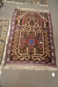 A small Middle Eastern wool floor rug decorated with an abstract panel on a mainly dark brown
