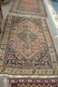 An antique Middle Eastern wool floor rug with central geometric panel on a mainly dark blue and