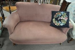 A small Victorian two seater sofa with curved arms and short carved legs and casters, 140cm wide