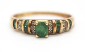 A 14ct emerald and diamond ring, set to centre with an oval faceted emerald in a four claw mount,
