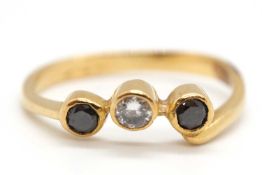 A three stone black and white diamond ring, the three round brilliant cut diamonds, all collet