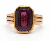 An unmarked garnet ring, the step cut garnet in a rubover mount with a three strand band of unmarked