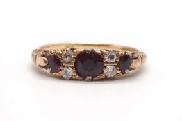 A garnet and diamond ring, the three round graduated garnets interspaced with two round mixed cut