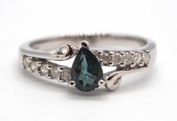 An 18ct white gold diamond and blue-green stone ring, the central blue-green pear shape stone set