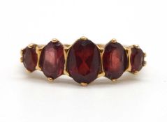 A 9ct garnet ring, the five oval graduated garnets, claw mounted with tapered shoulders and plain