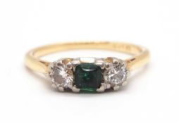 An emerald and diamond ring, the central square emerald with a round brilliant cut diamond to either