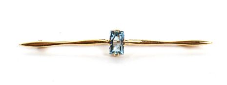 A 15ct aquamarine bar brooch, the mixed cut rectangular aquamarine in four double claws, set to a