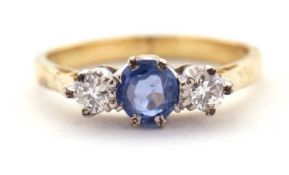 An 18ct sapphire and diamond ring, the central pale blue sapphire set to either side with a round