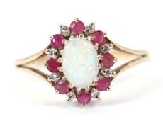 A 9ct opal, ruby and diamond ring, the oval opal cabochon surrounded by small round rubies and