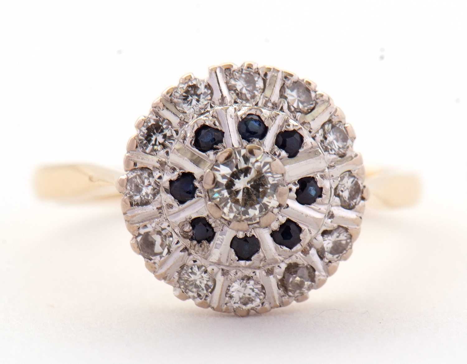 A sapphire and diamond cluster ring, the central round brilliant cut diamond surrounded by a ring of