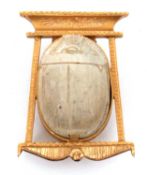 A scarab brooch, the carved stone scarab in a collet mount within a stylised Egyptian style frame,