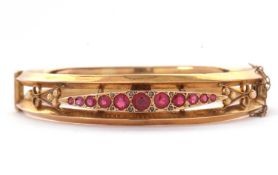 A 9ct ruby bangle, the hinged bangle set with a central marquise shape panel with graduated round