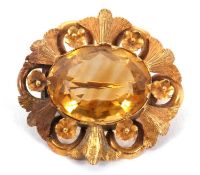 A citrine brooch, the oval citrine in a collet and claw mount surrounded by textured foliate design,