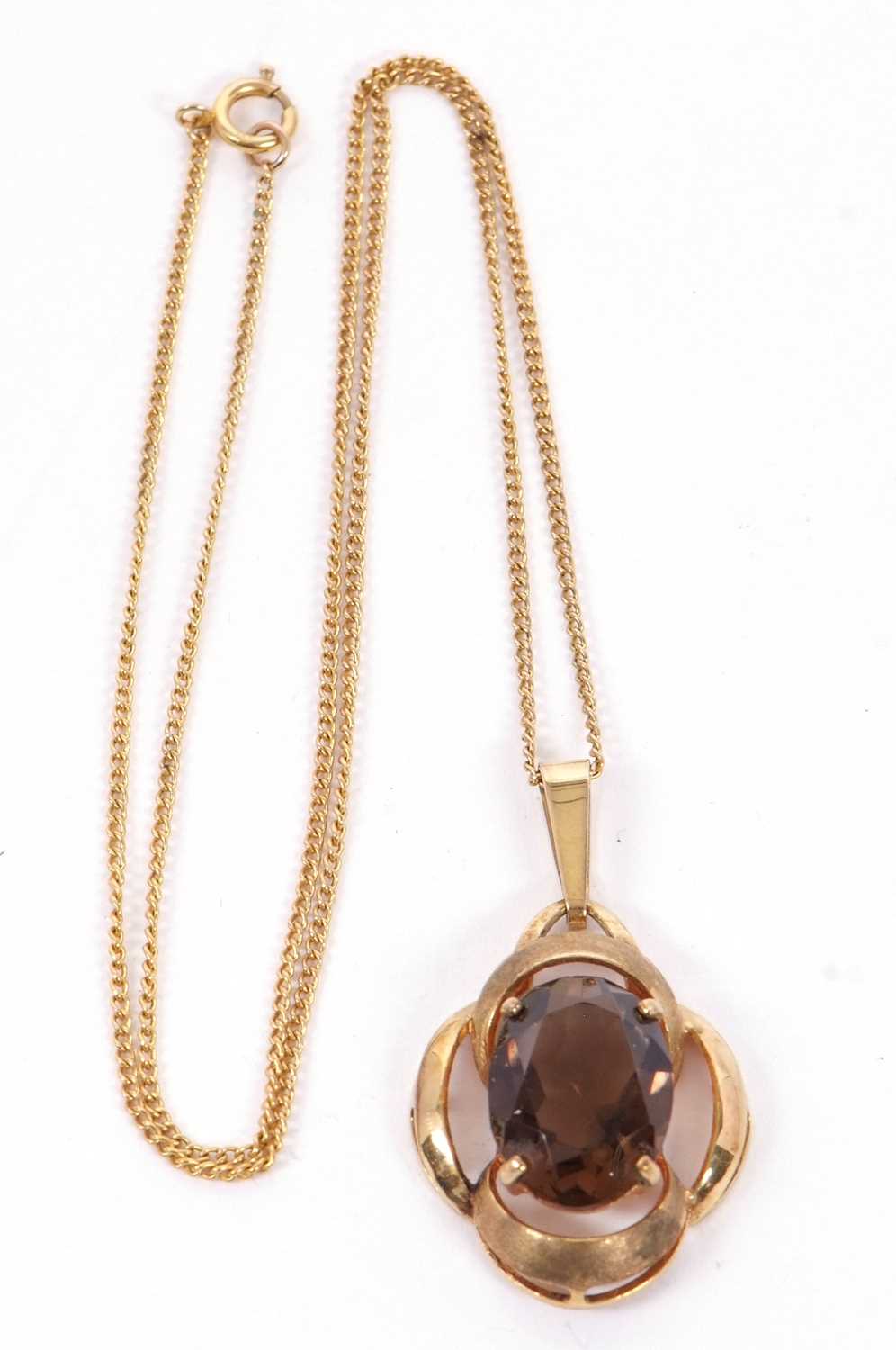 A smokey quartz pendant, the oval smokey quartz set within an openwork scalloped frame with