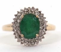 A 9ct emerald and diamond cluster ring, the oval emerald, approx. 9mm long, surrounded by two rows