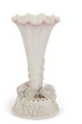 A Belleek trumpet shaped vase the base with finely modelled flower heads with a basket, Belique