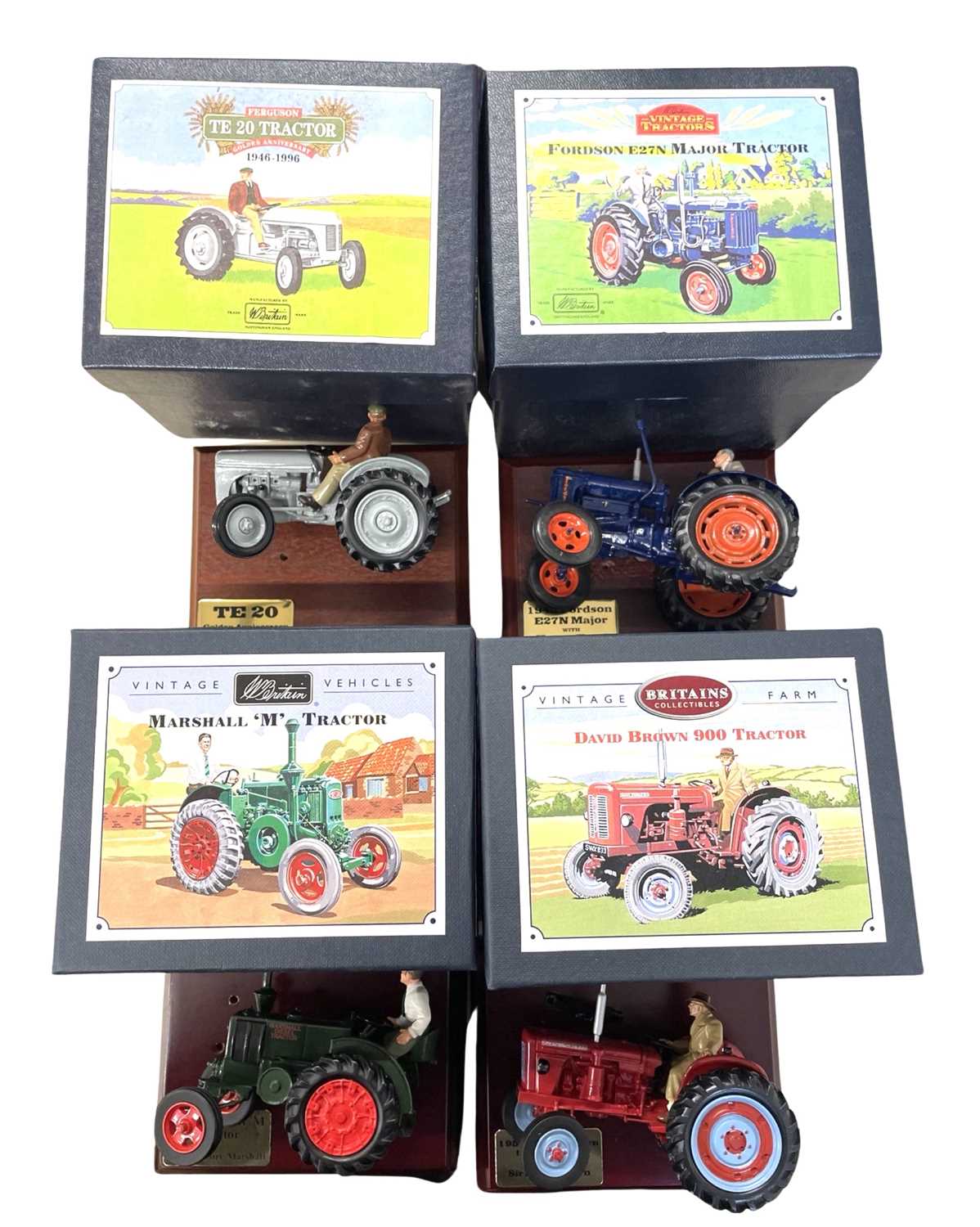 Four boxed Britains die-cast tractor models on wooden plinths, to include: - David Brown 900 -