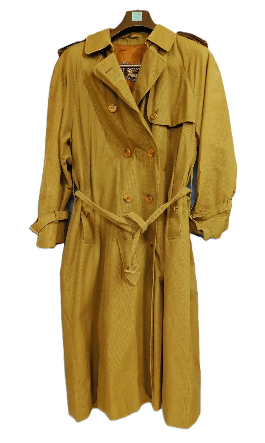 A lady's double breasted Burberry trench coat, in green check with brown buttons, belted waist and