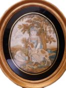 A 19th century silkwork picture, the oval scene of a girl with painted face, holding a spaniel besie