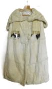 A full length white fur cape, with deep turn up shawl collar, two covered buttons and ermin trim,