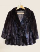 A lady's brown fur jacket, with hook fastening and faux buttons, with front slit pockets