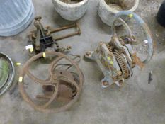 Two vintage flywheel winches together with a vintage metal framed grinding stone