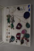 Small display case containing various polished stone pendants and other costume jewellery