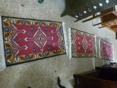 A set of three small modern rugs or prayer mats with large central red panels
