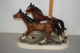 A large ceramic sculpture of two horses on oval frame