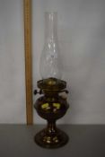 A metal oil lamp with glass chimney