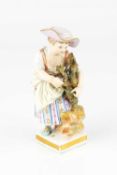 A 19th century Meissen small figure of a girl, with floral striped dress beside a vine, blue crossed