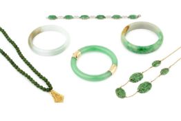 A 14k gold mounted jade hinged bangle, 7.6cm wide, two further pale mottled jade bangles, a 9ct gold