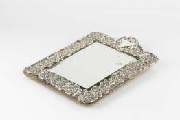 An Edwardian silver mounted dressing table mirror, repoussé decorated with fruits and flowers within