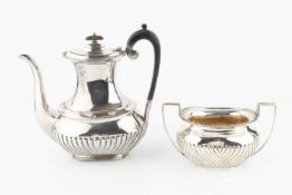 An Edwardian silver coffee pot, of part lobed form, with gadrooned border and ebonised handle and