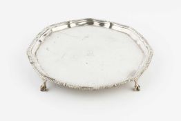 An Edwardian silver small salver, with shaped and gadrooned border, crested, on claw and ball feet