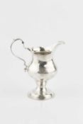 A George III silver cream jug, with shaped baluster body and leaf capped scroll handle on domed