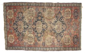 A red ground rug with blue central medallions. A blue stylized wave boarder. L212cm x W130cm.