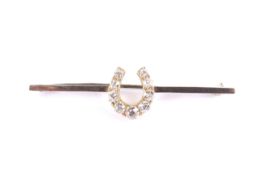 A late Victorian gold and diamond 'horseshoe' bar brooch. The nine graduated old-cut stones approx.
